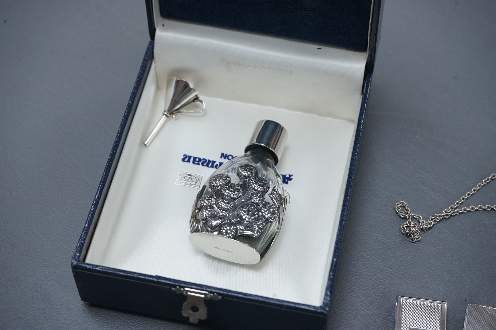 A group of mainly modern silver collectables including three assorted scent flasks and funnels by Ari D. Norman, two money clips, matchbox sleeve, napkin ring, pill box, three pendants including ingot and a pair of Victo